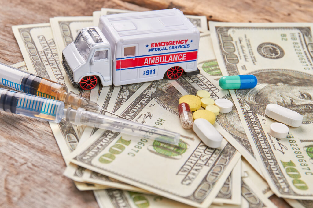 A photo of prescription drugs, money, and an ambulance close up.